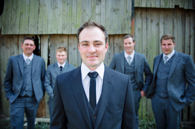 Groom with groomsmen in grey suits on barn door