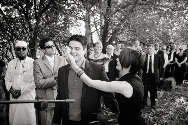 bride in black dress wiping grooms tears